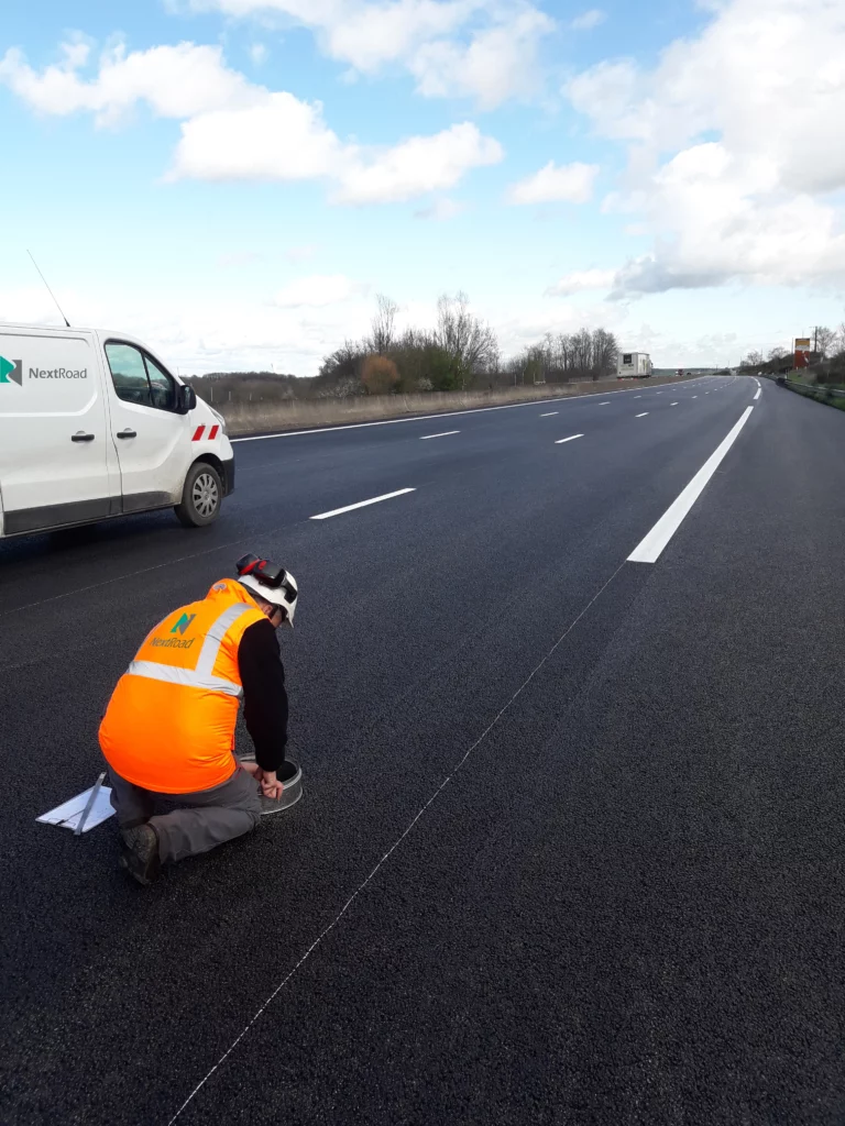 Technicien réalisant une intervention sur une chaussée autoroutière.